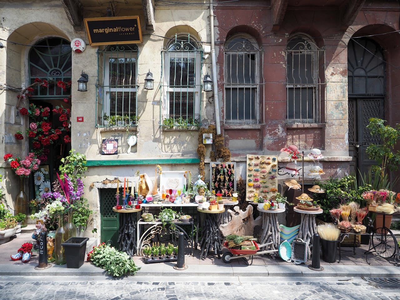 Colorful outdoor display of a florist in Istanbul, showcasing flowers and crafts against rustic building facade.